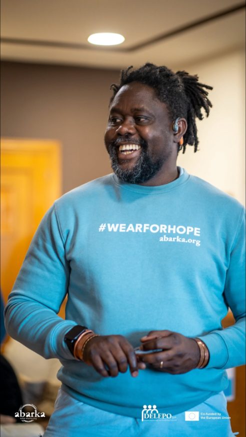 Clotaire Ntienou smiling, wearing an ABARKA #WEARFORHOPE sweatshirt